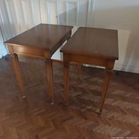 Pair of matching neoclassical style wooden side tables photographed together showing their tops and tapered legs.
