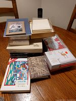 Photo showing a stacked assortment of boxed note cards, greeting cards including holiday designs and a UNICEF branded box on a wooden table.