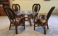 Set of four bamboo and rattan chairs arranged around a glass top table, showing overall style and design