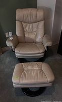 Full view of cream leather chair with high back and matching ottoman in front, showing overall shape and color.
