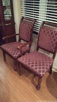 Two chairs shown side by side, one captain chair with armrests and one armless chair, both with reddish diamond patterned upholstery.