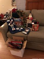Full view of sofa with Santa figurine, Christmas stockings, gift bags, and decorative wreath placed on and around it.