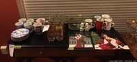 Overview of all items on table including plates, mugs, glasses, and plaques