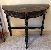 Front view of black demi lune table with hand painted Asian art on the tabletop and apron.