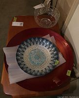 Three serving bowls displayed: crystal bowl on stand at back, large red wooden bowl, blue Turkish bowl with silver pattern.