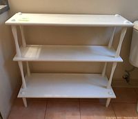 Front view of white painted wood three-tier shelf showing all three shelves with rounded corner caps on top and bottom.