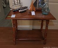 Front view of wooden side table showing rectangular surface and turned legs.