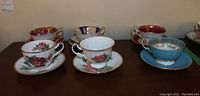 All six tea cup and saucer sets arranged in two rows showing variety of designs and colors