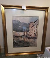 Full view of framed river scene print with sailboats and buildings along the waterfront.