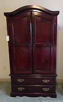 Front view of wood wardrobe armoire with closed doors and drawers visible