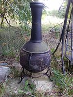 Full view of outdoor chiminea with chimney, mesh body and tripod stand