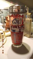 Front view of the vintage cocktail shaker with a metal lid featuring a colorful vintage bartender illustration in red and blue.