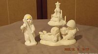 Photo of four vintage white textured Snow Babies figurines including three snow children and one snow tree with star topper.