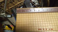 Close-up photo of the wooden base with grid pattern and the metal ruler on top with Milton Bradley branding and measurement markings in centimeters and inches.