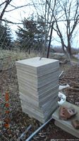 Tall stack of smaller-sized concrete patio stones outdoors, gray color, textured surface