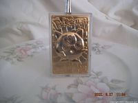 Front view of gold plated embossed Pokémon trading card featuring Puffer character in plastic protective case on floral backdrop.