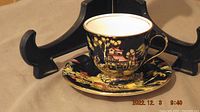 Photo of side view of one demitasse cup on matching saucer showing design and shape
