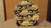 Royal Winton Pekin Black dinner plate with black background and colorful oriental motifs, gold trimmed edge. No chips or cracks visible. Shows characteristic crazing.