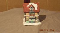 Photo of two-story ceramic house with red snow-covered roof, green door, and 'Smith' sign
