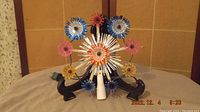 Multi-color vintage 1970s light up tree star with starburst shaped light covers in various colors on a black stand.