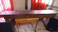 Full view of the walnut mantel showing the rectangular top surface and front profile supported by a table beneath for display.