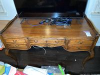 Front view of vintage wooden desk with five drawers, showing scratches and wear.