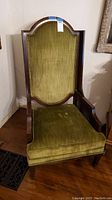 Front view of vintage high back armchair showing green velvet upholstery, wood frame, and cushion seat.