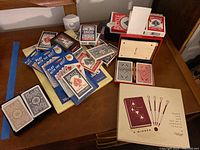 Photo of the playing cards and bridge score pad materials laid out on a table showing multiple Bicycle playing card decks in various packaging.