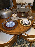 Photo showing entire lot on wooden dining table including Liberty Blue plate, serving platters, lazy susans, metal tiered stand, and aluminum covered dish.
