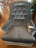 Front view of the vintage gray fabric rocking swivel armed chair showing tufted buttons on seat, arms, and backrest.
