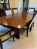 Overall view of extendable dining table with chairs arranged around it.