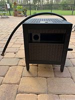 Front view of the metal hose reel cabinet showing the textured panel and hose attachment.