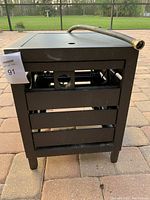 Front and side views of black metal hose reel cabinet with visible hose connections and manual crank.