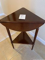 Photo of the table folded into a triangle from the top, showing drop leaf design and lower shelf.