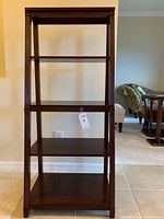 Front view of the four-tier ladder floor display showing all shelves in cherry wood finish.