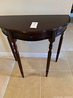 Wooden half moon entry table in cherry finish showing front and leg details