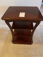 Front view of Bombay Company mahogany side table showing four shelves and elegant curved supports.