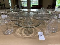 Full view of all glass items, including cake stands, domes, olive jar with spoon, oil and vinegar cruet, nightstand water carafe and glass.