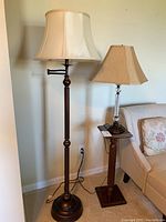 Photo of two lamps: metal body floor lamp with swing arm and metal/cut glass table lamp. Lamps are illuminated and bulbs included. Floor lamp approx 63x19 inches, table lamp approx 28x20 inches.