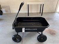 Front side view of the black Gorilla utility dump cart on four wheels with handle, showing the overall structure.