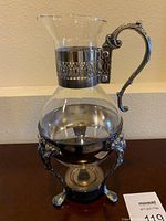 Glass coffee/tea carafe sitting in silver plated warming stand with tea light holder.