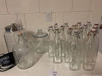 Glass bottles with swing top closures and various glass jars on a table.