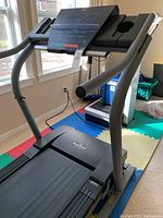 Full view of NordicTrack treadmill showing black tread belt, curved handles, and base with the NordicTrack logo visible.