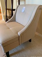 Side angle showing the curved armrest, seat cushion, and fabric texture of the linen accent chair.