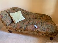 Full view of left-arm chaise lounge sofa with floral upholstery and tufted seat and backrest, including the two cushions placed on it.