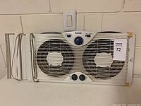 Front view of Holmes double reversible window fan showing two fans, dial, and switch controls, with side panels attached.