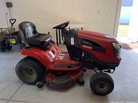 Left side profile of red and black riding tractor showing cutting deck