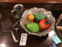 Full lot view showing signed metal bowl with five glass fruit pieces, pewter mug, and two wine corkscrews on wooden surface.