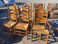 Set of six wooden ladder back chairs arranged outside, showing overall condition and design.