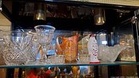 Wide side view of all glass items on a glass shelf showing details and arrangement.